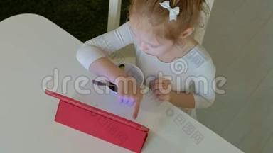 小女孩吃和玩电脑平板电脑。 网上冲浪